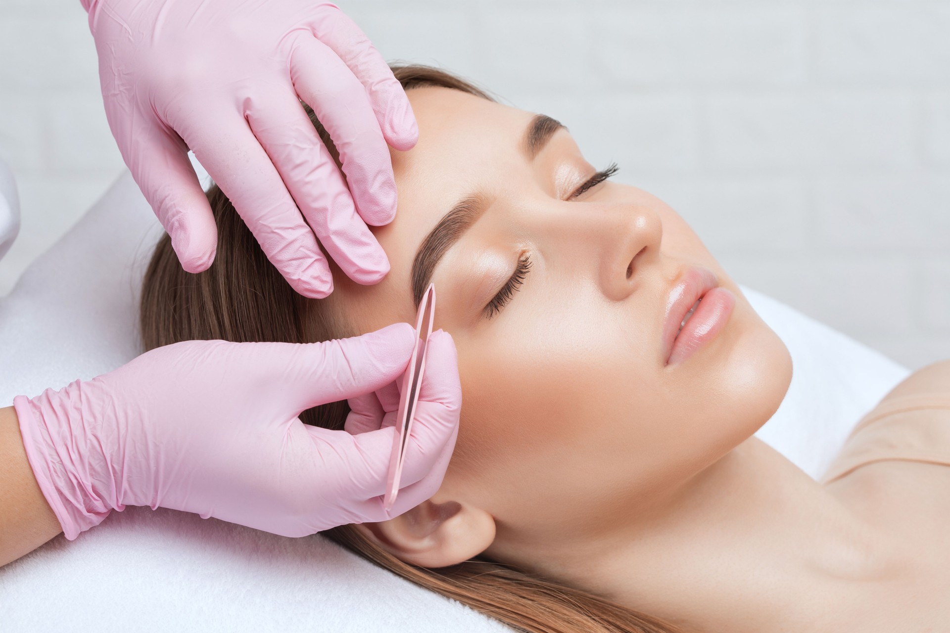 La maquilleuse arrache les sourcils après la procédure de coloration. Maquillage professionnel et soins du visage.